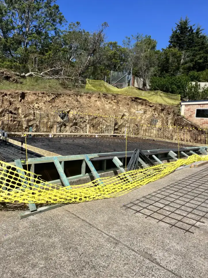 A core-filled besser block retaining wall part-way through construction on a cut batter.