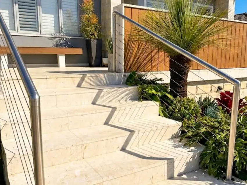 Travertine feature steps running up through native planting under a blue sky.
