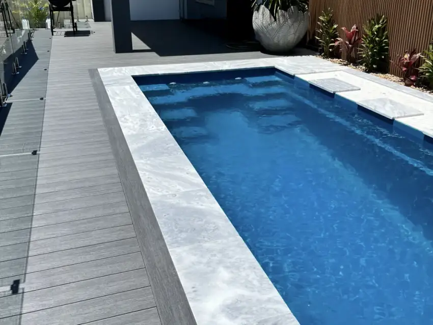 A finished lap pool with composite decking beside a covered alfresco kitchen.